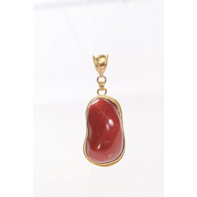 A lovely coral pendant with 21 karat gold trim and mobile bail. The surface of the coral is highly polished and smooth,...