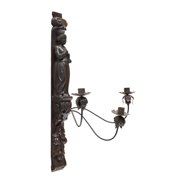 Probably a fragment of a French church paneling, this hand carved wooden candle sconce from France features iron...