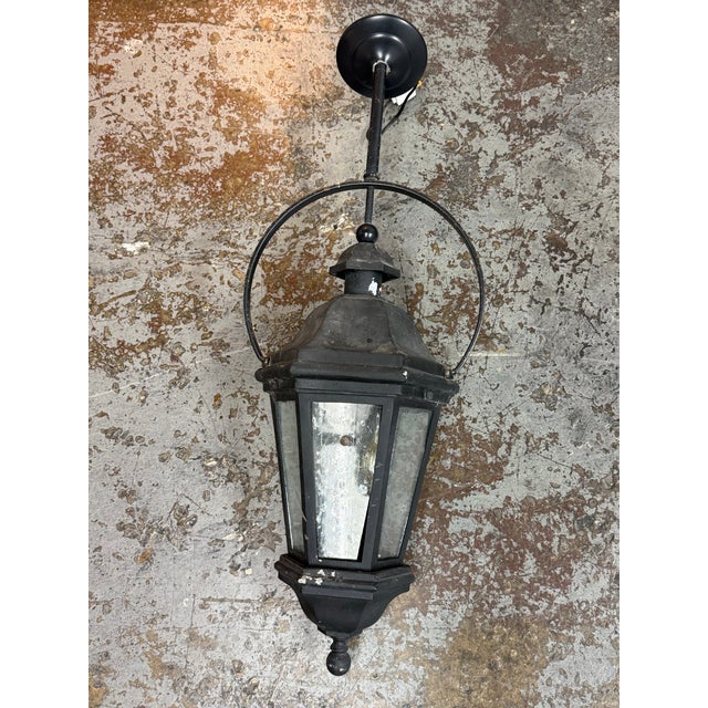 Design Plus Gallery presents the Traditional Black Metal Seeded Glass Lantern Wall Sconce. The fixture has a hexagonal...