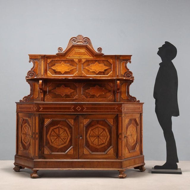 Umbertina walnut sideboard with a rounded shape. Geometric inlays in various woods throughout. The top features a shelf...