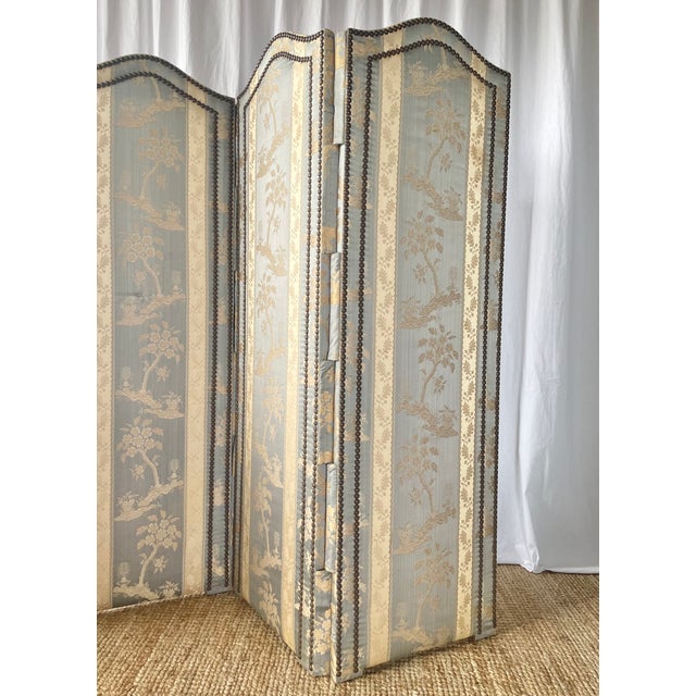 An elegant antique three-panel screen, dating from the 1920s/1930s, resting on a wooden frame and entirely covered in...