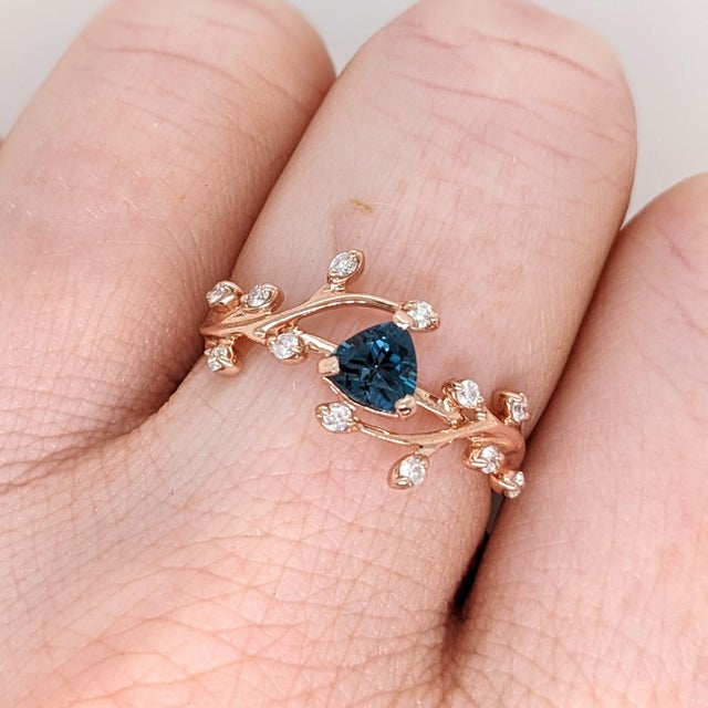 An AAA London blue topaz glows in a deep, steely blue at the centre of this solid 14K rose gold ring, surrounded by twelve...