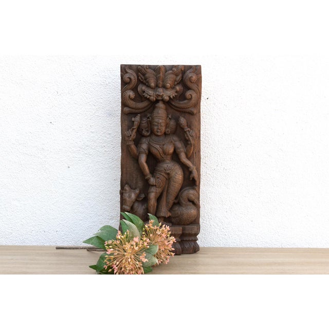 This antique carved wood panel, a relic of South Indian artistry and spiritual devotion, depicts Vishnu, the Hindu god of...