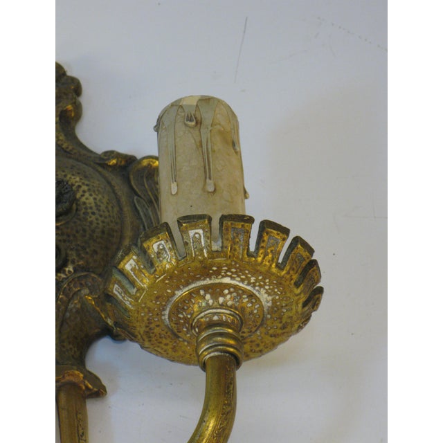 The product is a medium-sized Wall Sconce Electric in an elegant bronze Empire style, featuring an embossed pattern...