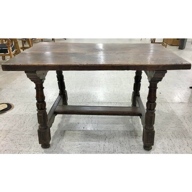 Italian, 18th century. Baroque walnut dining or tavern table having a thick walnut top above turned legs with Walnut...