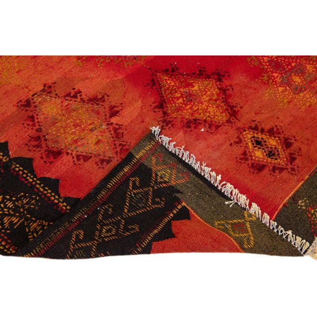 Beautiful vintage Turkish Kilim hand-knotted wool rug with a red field. This piece has a black frame and multicolor...