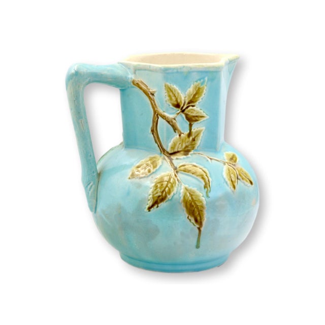 Generously sized antique English majolica jug, richly molded with wild dogwood blooms and leafy branches set against a...