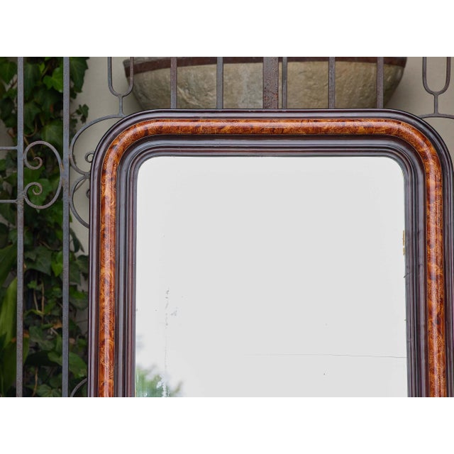 A French Louis-Philippe style mirror from circa 1920 featuring a richly colored faux tortoiseshell frame with rounded...