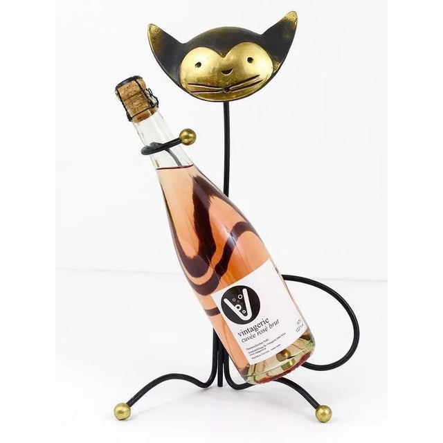 A beautiful wine caddy bottle holder, made of brass. A very humorous design by Walter Bosse, executed by Hertha Baller...