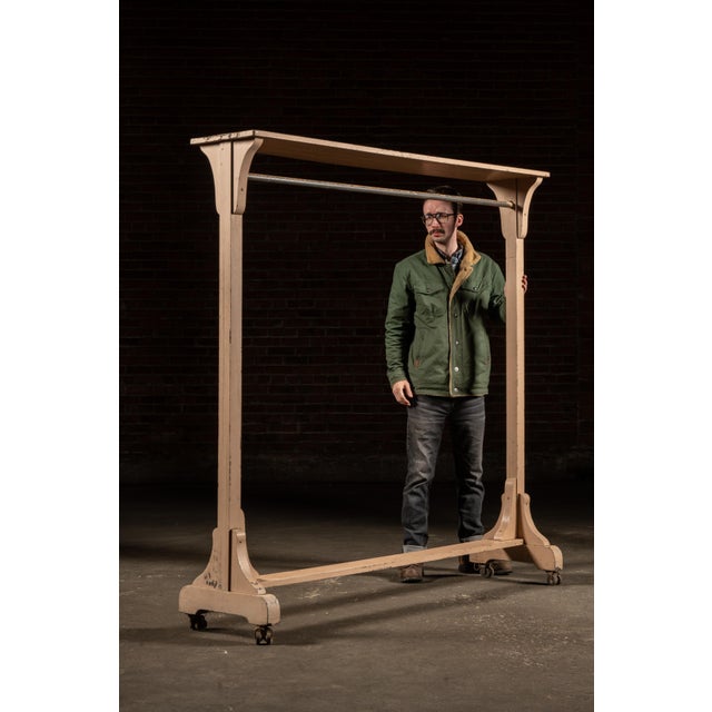 Painted wooden garment rack with a long, low-profile rectangular top rail supported by turned uprights and curved bracket...