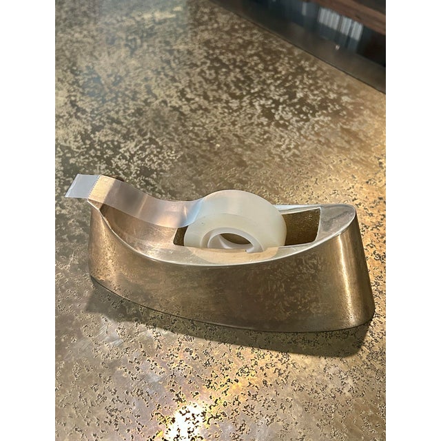 This is a 1970s Modernist solid brass tape dispenser with a sleek, sculptural silhouette and beautifully polished finish....