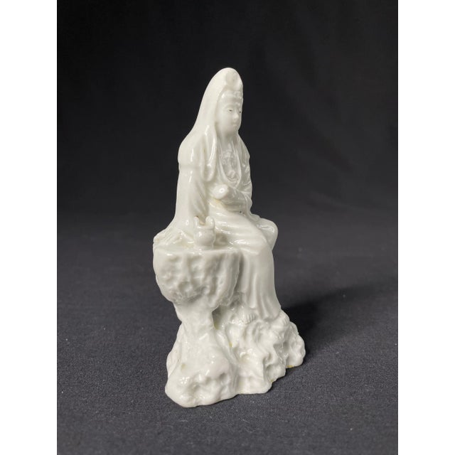 A charming porcelain figure of seated Guanyin, goddess of compassion and mercy. Seated on a limestone plinth with the...
