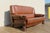 Exceptional vintage 1970s brown leather sofa featuring a substantial sculptural wood frame paired with beautifully...