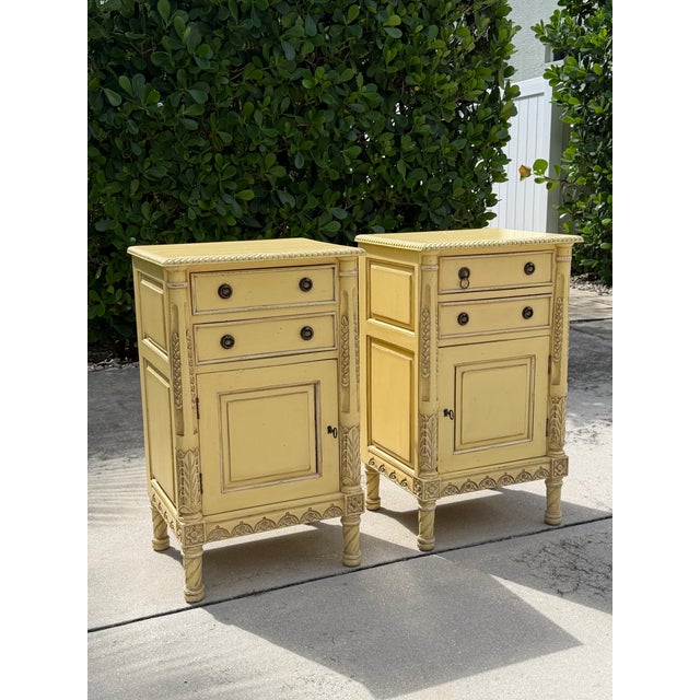 Pair of vintage carved wood nightstands with a warm antique yellow finish and extensive decorative detailing. Each...