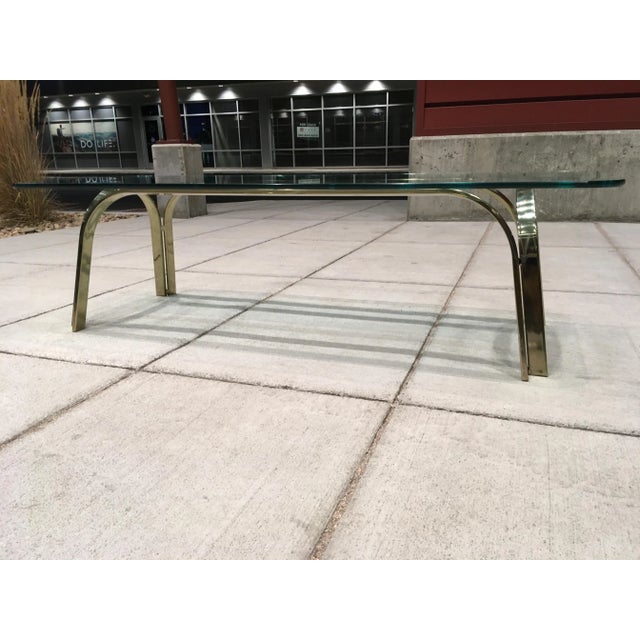 Mid-century modern sculptural brass plated thick glass top cocktail table after Roger Sprunger for Dunbar, circa 1970s.