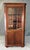 This vintage wooden corner cabinet features a classic glass-paneled upper door with arched muntins, perfect for displaying...