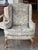 Wingback chair upholstered in floral needlepoint fabric with shaped wings and rolled arms. Loose seat cushion over an...