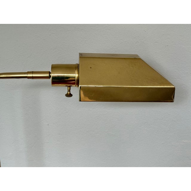 Late 20th century polished brass pharmacy floor lamp with an adjustable height stem and a rectangular hooded shade....