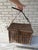 This vintage wicker fishing basket features a rustic hinged lid and a sturdy leather strap for carrying.
