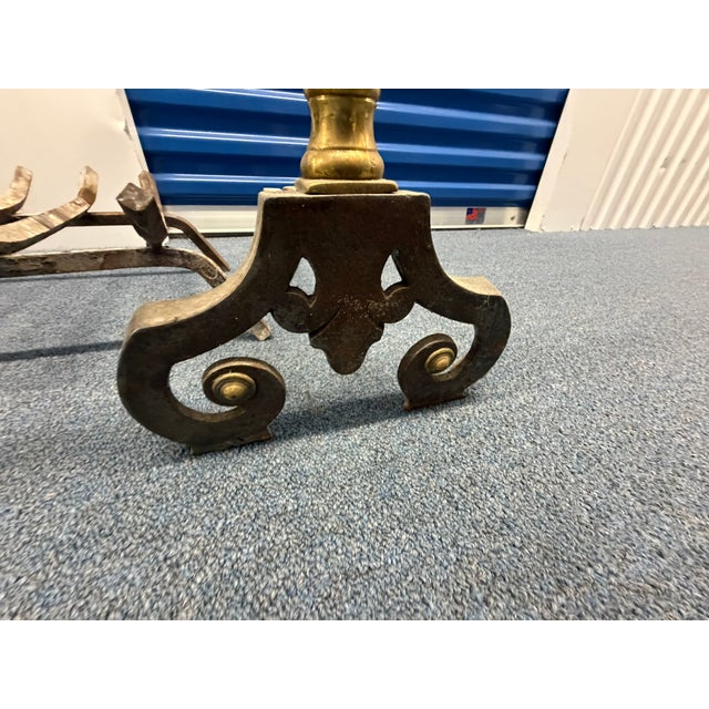 This antique brass and iron fireplace set includes a beautifully crafted pair of andirons topped with turned brass finials...