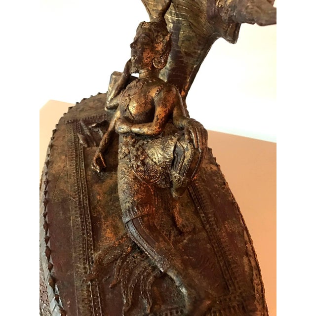 Depicting Buddha in his royal attires resting on a throne made of coiled naga body and sheltered by the canopy of the...