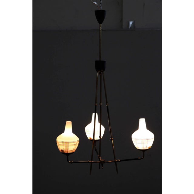 Chandelier in polished brass with ball joints and black lacquered parts, white opal duplex glass diffusers, with...