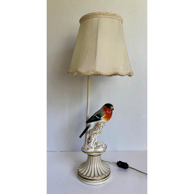 This charming vintage table lamp features a beautifully detailed porcelain bird perched atop a carved wood base with...
