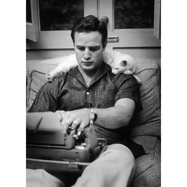 "Marlon Brando" by Murray Garrett 1954: EXCLUSIVE American actor Marlon Brando sits on a sofa with a typewriter in his lap...