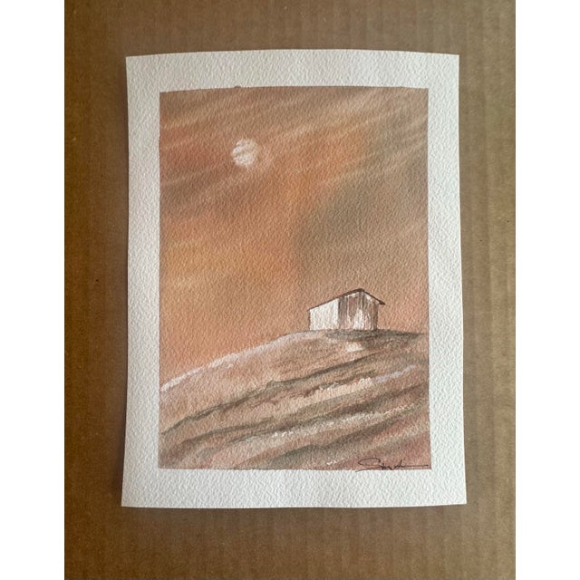 This warm-toned watercolor depicts a quaint countryside scene featuring a small, rustic cottage perched atop rolling...
