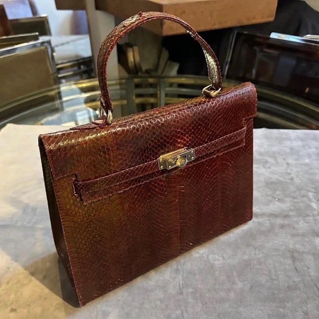 This elegant vintage leather handbag from the 1970s exudes timeless sophistication with its structured silhouette and rich...