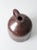 An antique stoneware jug with a rich brown glaze, rounded body, narrow neck, and gracefully curved handle. The deep,...