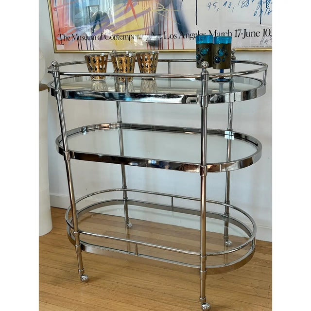 This stylish, modern and sleek vintage bar cart features a heavy chrome construction with 3 thick clear glass oval shelves...
