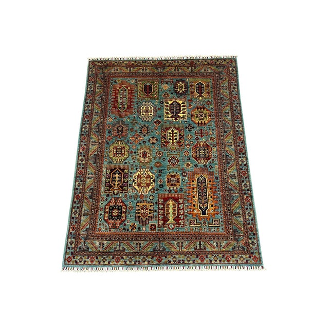 This Kazak style area rug has a turquoise blue field filled with repeating Tree of Life motifs, small flowers, and...