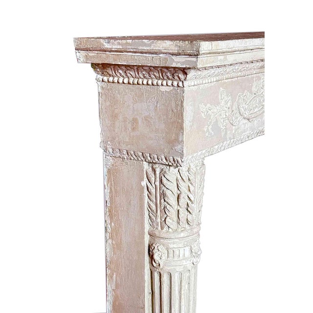 Antique Neoclassical Louis XVI-style French fireplace surround features a finely carved ribboned garland frieze with...