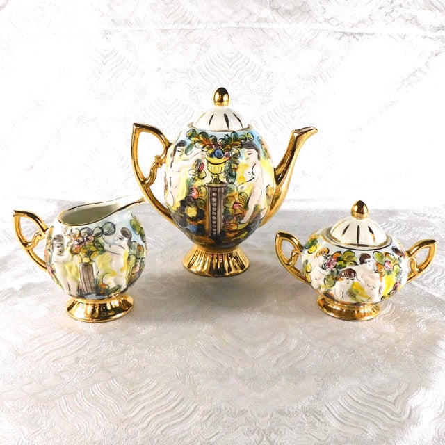 This is a thirteen piece tea set in white with a lot of other colors, a lot of gold trim and naked people on it. It...