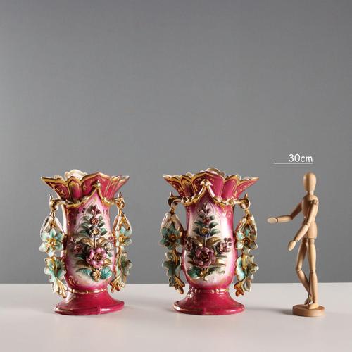 A pair of white and deep pink porcelain vases with polychrome and gold decoration. The body features a raised floral...