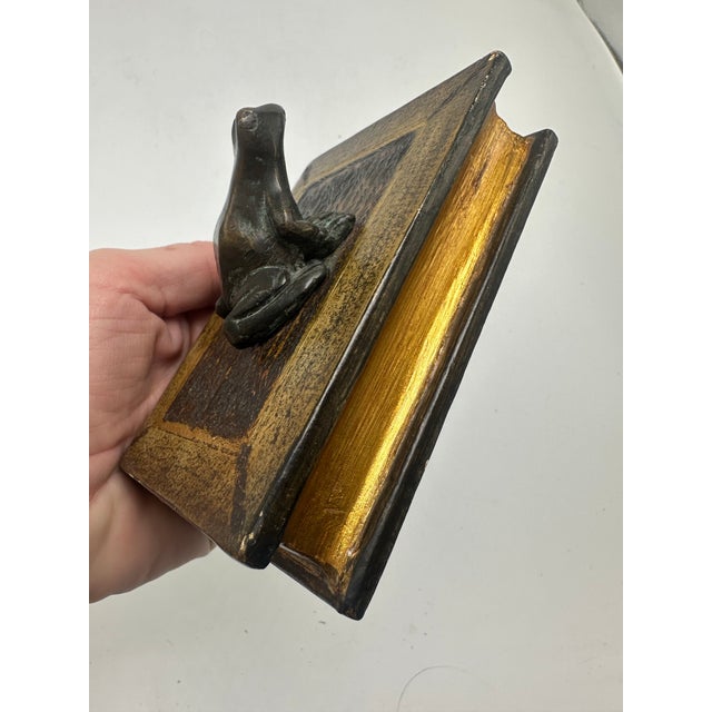 This is a charming small figurine in the form of a decorative box shaped like an antique book, topped with a bronze or...