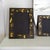 A pair of finely hand-painted black lacquered chinoiserie picture frames depicting people, pagoda temples, trees, and...