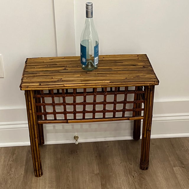 Charming vintage pencil reed bamboo side table featuring a decorative trellis apron and warm honey-toned finish. The...