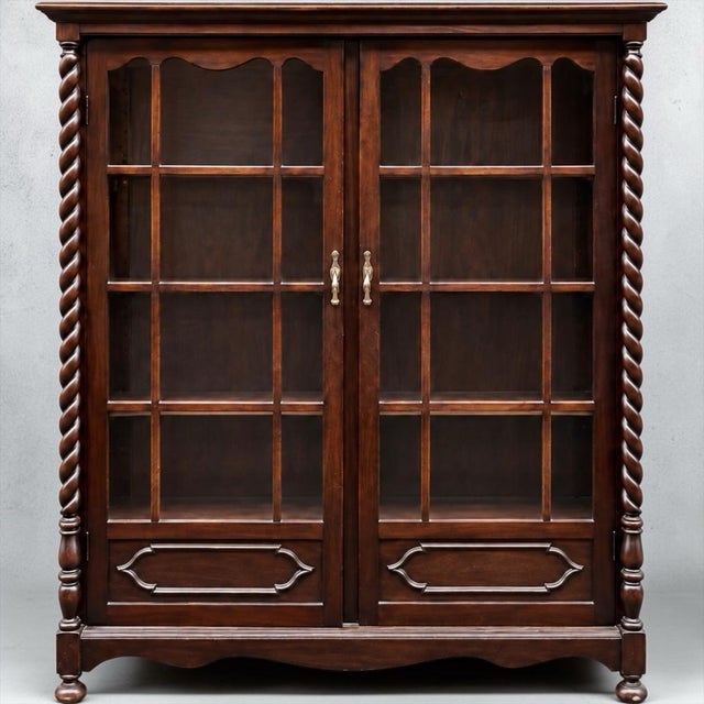 This is an American Victorian era carved mahogany barley twist bookcase or display cabinet. It dates roughly to 1900. The...