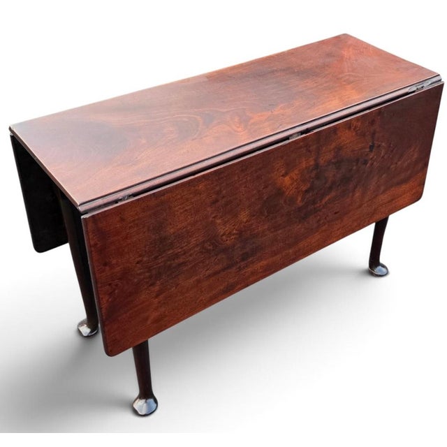 A fine and increasingly scarce English George III period drop-leaf gateleg dining table, handcrafted in solid Cuban...
