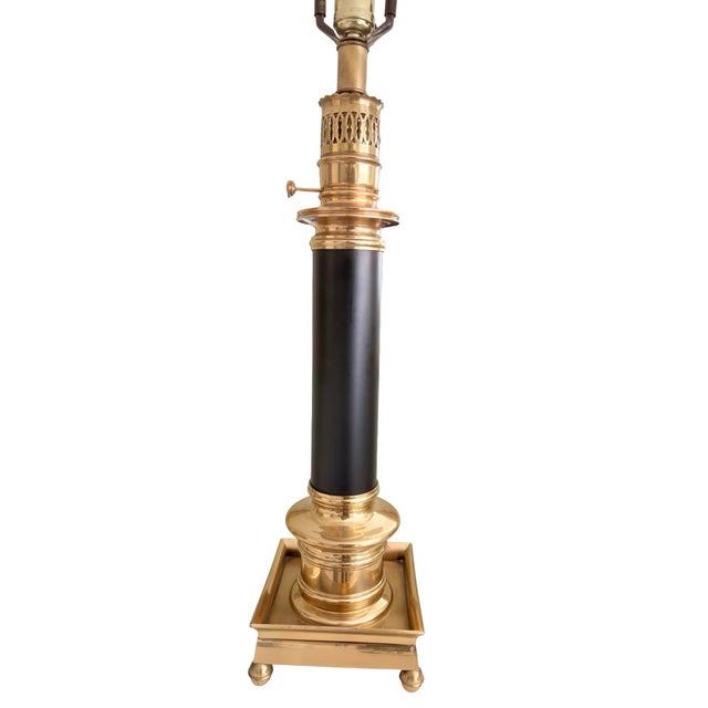 Classic vintage brass table lamp featuring a black column body, decorative pierced brass detailing, and a square brass...