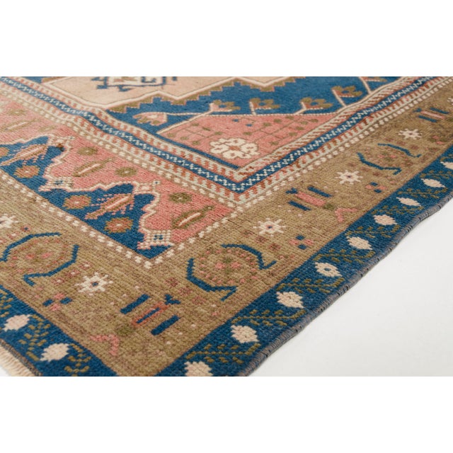 This is a vintage Turkish Oushak rug from the Mid 20th Century. The piece was hand-knotted.