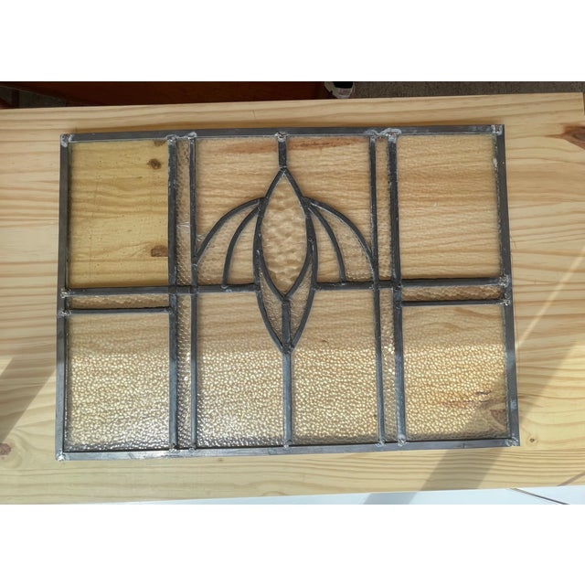 This vintage leaded glass window panel features a geometric design with a central stylized floral motif.The piece is...