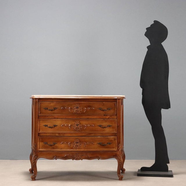 Walnut chest of drawers in the late Baroque style. Three-drawer curved front with central floral carvings, curved legs...