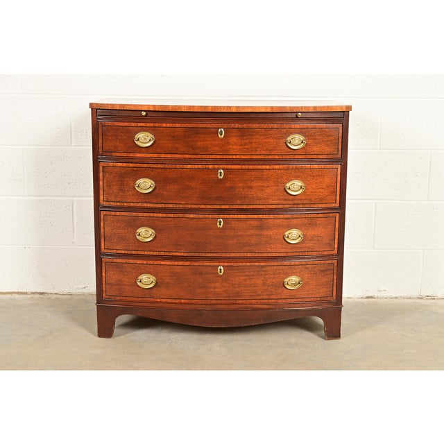A gorgeous Georgian or Chippendale style bow front four-drawer commode, dresser, or bachelor chest of drawers By Baker...
