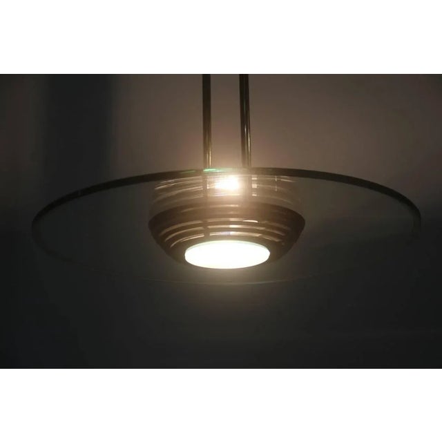 This minimalist ceiling lamp with a glass disc dates to the 1970s. Up to 250V (Europe/UK Standard).The wiring of this item...