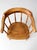 An antique Windsor captain’s chair with a graceful low, wraparound back, turned spindle supports, and a shaped wooden...