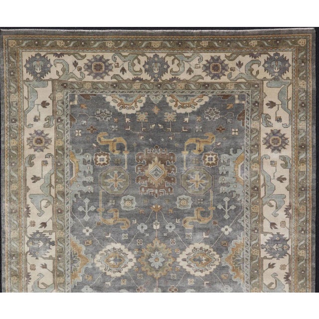 Measures 9'10 x 14'2 This modern day Oushak was hand-knotted with wool in India during the 2010's. The moody earthy colors...