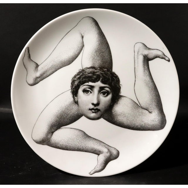 "Sicilian Surrealism": Fornasetti "Tema e Variazioni" Trinacria Plate, (Face with Three Legs), 1990's A striking and...